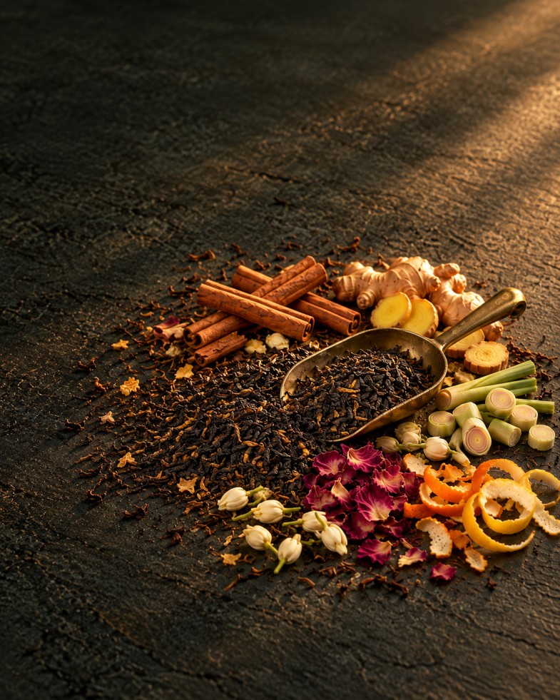 Ceylon tea leaves and whole spices laid out on a dark surface